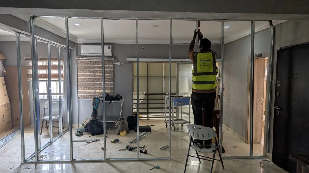 Installer working on metal partition framing during interior construction